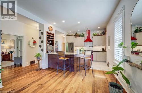 Hardwood flooring, recessed lighting, kitchen island with seating, built-in wine storage, and a striking red range hood - 59 Allen Street W, Waterloo, ON 