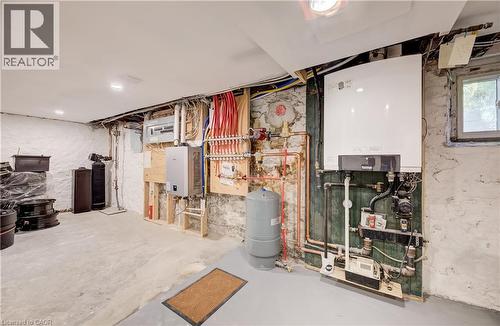 Concrete flooring, exposed stone foundation wall, utility area with visible plumbing, recessed lighting, and a single window - 59 Allen Street W, Waterloo, ON 