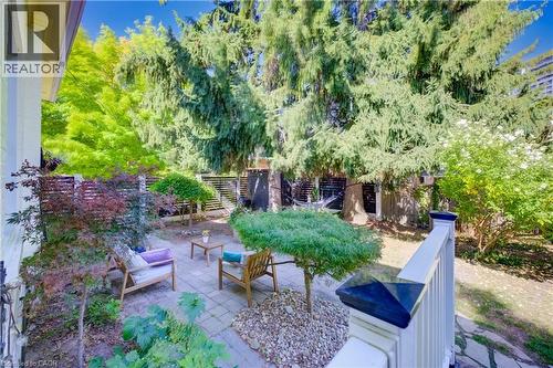 Paved patio area, privacy fencing, mature trees, landscaped garden beds, and stone path - 59 Allen Street W, Waterloo, ON 