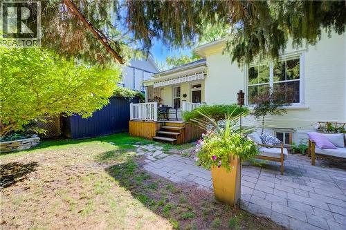 Expansive backyard featuring a stone patio, elevated wood deck with white railings, and mature trees - 59 Allen Street W, Waterloo, ON 