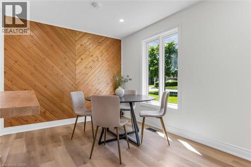 Herringbone wood-finish accent wall in a dining area featuring light wood-finish flooring, recessed lighting, and a large window with white trim - 49 Grove Avenue, St. Catharines, ON 