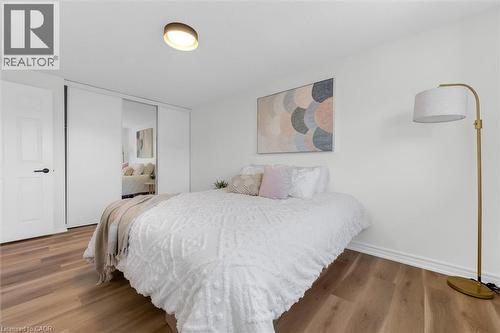 Bedroom featuring wood-finish flooring, white baseboards, and a contemporary ceiling light fixture - 49 Grove Avenue, St. Catharines, ON 