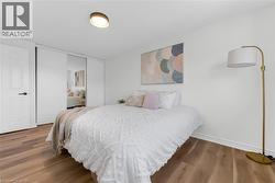 Bedroom featuring wood-finish flooring, white baseboards, and a contemporary ceiling light fixture - 