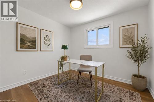 Bright room featuring wood-finish flooring, white baseboards, and a window with white trim - 49 Grove Avenue, St. Catharines, ON 