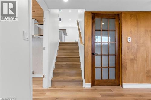 Wood-finish flooring throughout, complemented by a light wood staircase with a white handrail - 49 Grove Avenue, St. Catharines, ON 