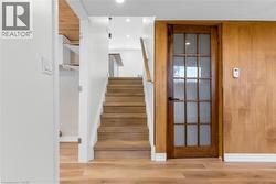 Wood-finish flooring throughout, complemented by a light wood staircase with a white handrail - 