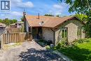 Stone facade residence featuring a brown shingle roof, a paved driveway, and a front porch with a dark metal railing - 49 Grove Avenue, St. Catharines, ON 