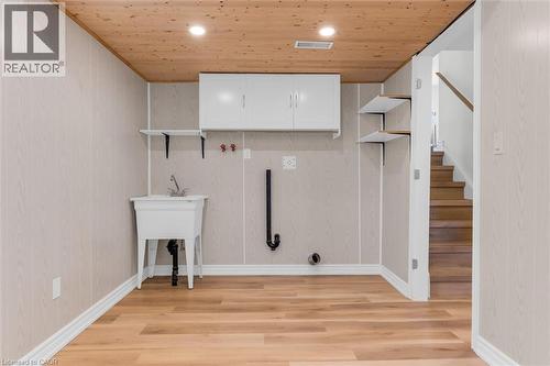 Utility area featuring wood-finish flooring, light-toned wall paneling, a wooden plank ceiling, recessed lighting, and a utility sink - 49 Grove Avenue, St. Catharines, ON 