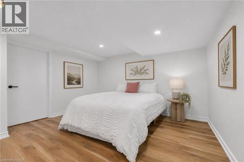 Bedroom featuring wood-finish flooring, recessed lighting, white walls, and white trim - 49 Grove Avenue, St. Catharines, ON 