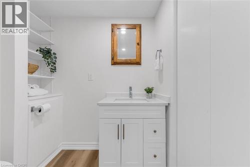 Bathroom featuring a white vanity with an integrated sink, a light-toned countertop, and wood-finish flooring - 49 Grove Avenue, St. Catharines, ON 