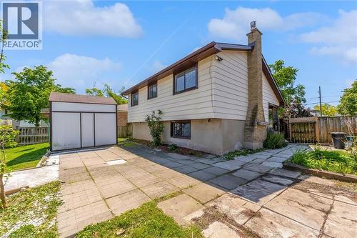 Side yard featuring a paver patio, detached storage shed, and a brick chimney - 49 Grove Avenue, St. Catharines, ON 