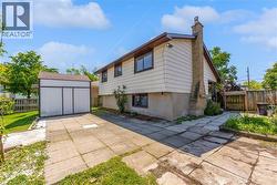 Side yard featuring a paver patio, detached storage shed, and a brick chimney - 