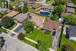 Expansive suburban property featuring a large manicured lawn, paved driveway, mature trees, and a brown shingle roof - 