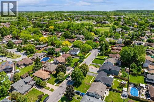 Aerial perspective showcasing a residential neighborhood with mature trees, green spaces, and multiple properties featuring private swimming pools - 49 Grove Avenue, St. Catharines, ON 
