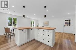 Spacious open-concept living area featuring an L-shaped island with a wood-finish countertop and white cabinetry - 