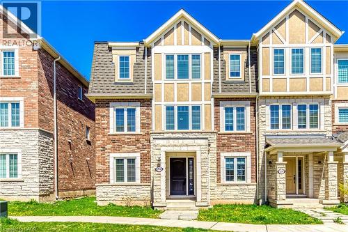 Three-story townhome featuring a stone and brick exterior, multi-pane windows, and a prominent front entrance - 212 Ellen Davidson Drive, Oakville, ON 