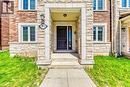 Brick and stone facade featuring a covered entry, exterior lighting, and a dark-paneled front door - 212 Ellen Davidson Drive, Oakville, ON 