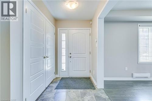 Entryway with gray tile flooring, a white paneled entry door with sidelight, and double-door storage - 212 Ellen Davidson Drive, Oakville, ON 
