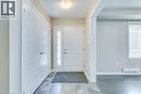Entryway with gray tile flooring, a white paneled entry door with sidelight, and double-door storage - 212 Ellen Davidson Drive, Oakville, ON 