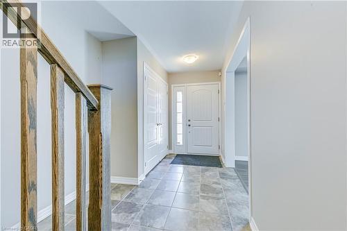 Foyer featuring a paneled entry door with sidelights, tile flooring, wood railing, and a flush mount ceiling light - 212 Ellen Davidson Drive, Oakville, ON 