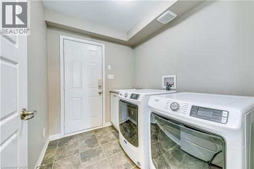 Laundry area featuring tile flooring, a utility sink, and white cabinetry - 212 Ellen Davidson Drive, Oakville, ON 