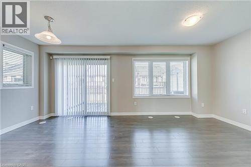 Wood-finish flooring, multiple windows with blinds, sliding glass door, and two ceiling-mounted light fixtures - 212 Ellen Davidson Drive, Oakville, ON 