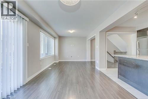 Spacious room featuring wood-finish flooring, a large window, and a glass-paneled sliding door - 212 Ellen Davidson Drive, Oakville, ON 