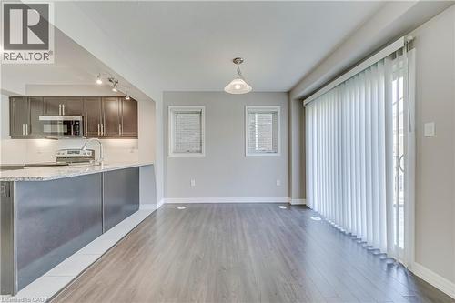 Open-concept layout featuring wood-finish flooring, a kitchen with dark cabinetry and light-toned countertops, and a sliding glass door - 212 Ellen Davidson Drive, Oakville, ON 
