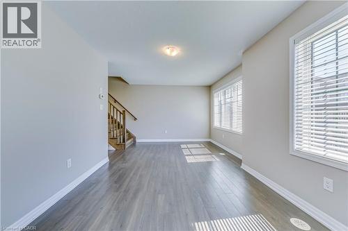 Recessed ceiling fixture, wood-finish flooring, staircase with wood railing, large windows with blinds, and light neutral wall finishes - 212 Ellen Davidson Drive, Oakville, ON 