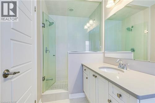 Spacious bathroom featuring a glass-enclosed shower, white vanity with integrated sink, chrome faucet, and overhead vanity lighting - 212 Ellen Davidson Drive, Oakville, ON 