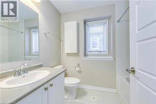Bathroom featuring a vanity with an integrated sink, a wall-mounted storage cabinet, and a bathtub with tiled surround - 212 Ellen Davidson Drive, Oakville, ON 