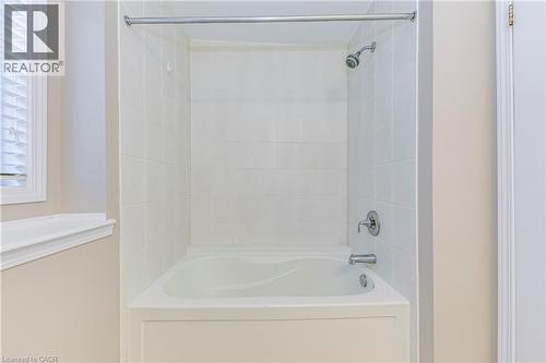 Bathtub and shower combination featuring white subway tile surround, chrome fixtures, and a white window with blinds - 212 Ellen Davidson Drive, Oakville, ON 