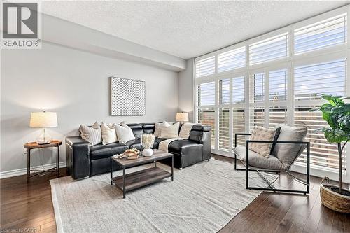 Expansive window wall with plantation shutters, dark wood-finish flooring, and recessed lighting - 427 Aberdeen Avenue Unit# 105, Hamilton, ON 