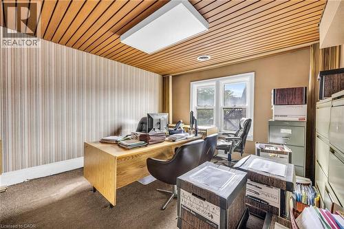 Wood-paneled ceiling with an integrated rectangular light fixture, dual windows, and carpet flooring - 414 Main Street E, Hamilton, ON 