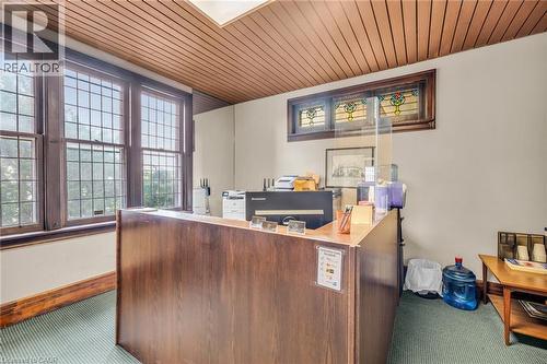 Wood-paneled ceiling, stained-glass transom windows, grid-pattern windows, wood-paneled reception desk, and textured green carpeting - 414 Main Street E, Hamilton, ON 