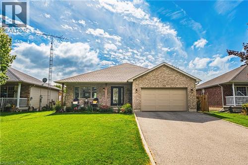 Brick exterior with an attached garage, paved driveway, and covered front porch - 915 St George Street, Port Dover, ON 