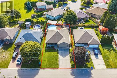Expansive property featuring a gabled roof, attached garage, well-maintained lawn, paved driveway, and mature landscaping - 915 St George Street, Port Dover, ON 