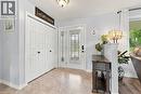 Entryway with paneled bifold closet doors, decorative glass panel entry door, and light-toned flooring - 915 St George Street, Port Dover, ON 