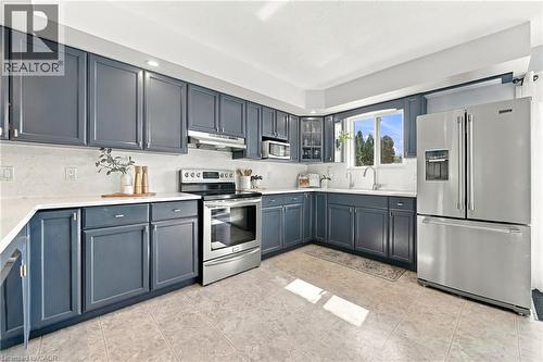 Kitchen featuring blue cabinetry, light countertops, stainless steel appliances, and tile flooring - 915 St George Street, Port Dover, ON 