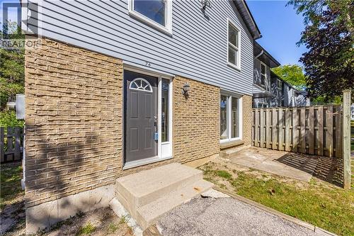 Brick and siding exterior with a dark-paneled entry door, arched transom window, and exterior light fixture - 70 Fiddlers Green Road Unit# 74, London, ON 