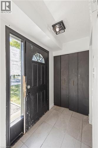Entryway featuring a decorative transom window above the door, side light window, flush mount ceiling light fixture, bi-fold closet doors, and tiled flooring - 70 Fiddlers Green Road Unit# 74, London, ON 