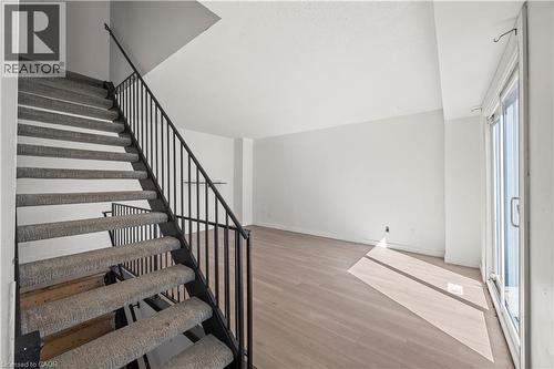 Staircase with carpeted treads and black metal railing, wood-finish flooring, and sliding glass door - 70 Fiddlers Green Road Unit# 74, London, ON 