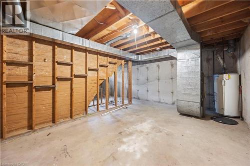 Unfinished basement featuring exposed wood joists, concrete foundation walls, and a water heater - 70 Fiddlers Green Road Unit# 74, London, ON 
