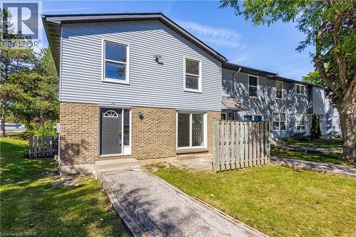 Light blue siding exterior with a dark gray entry door, complemented by a light brown brick facade - 70 Fiddlers Green Road Unit# 74, London, ON 