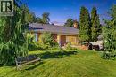 Brick exterior with a dark roofline, front steps, and a landscaped front yard featuring mature trees and a sloped lawn - 940 Harvey Place, Halton, ON 