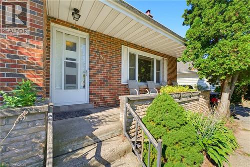 Brick exterior with a covered front porch, white-framed windows, and built-in stone planters - 940 Harvey Place, Halton, ON 