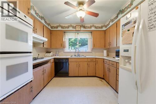Kitchen featuring wood-finish cabinetry, white appliances, wall oven, and ceiling fan - 940 Harvey Place, Halton, ON 
