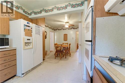 Wood-finish cabinetry, white appliances, and light-colored flooring - 940 Harvey Place, Halton, ON 