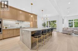 Light wood-finish flooring, full-height cabinetry, kitchen island with seating, stainless steel appliances, and a sliding glass door - 