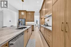 Modern kitchen featuring wood-finish cabinetry, light-toned countertops, and light wood-finish flooring - 